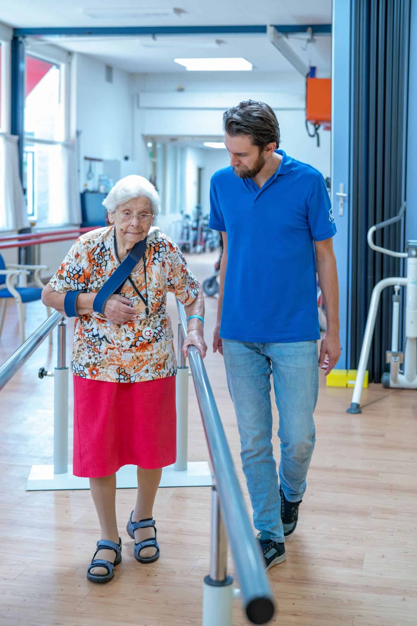 Een fysiotherapeut begeleidt een bewoner bij het lopen