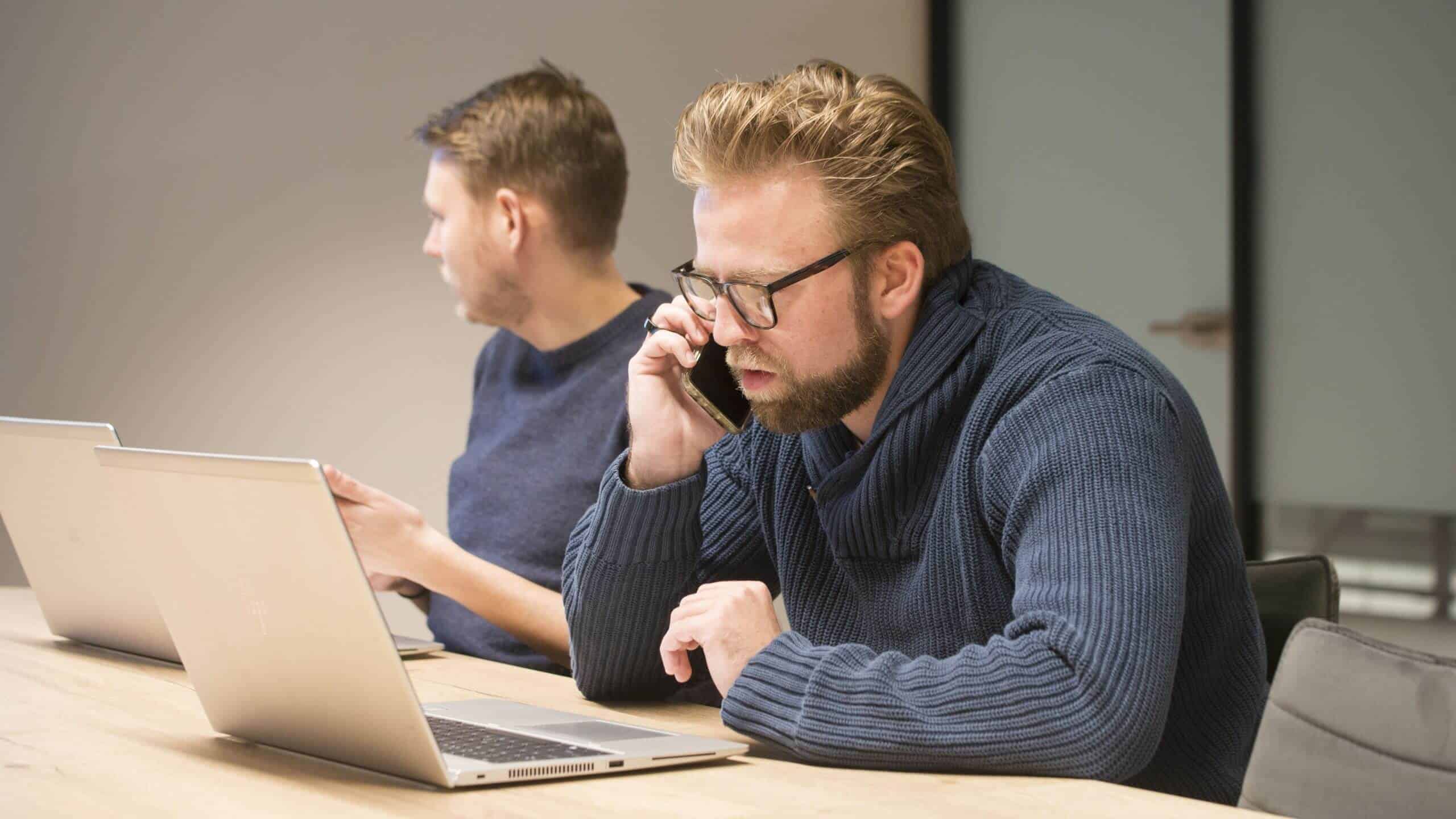 Een collega belt met een klant vanachter zijn laptop