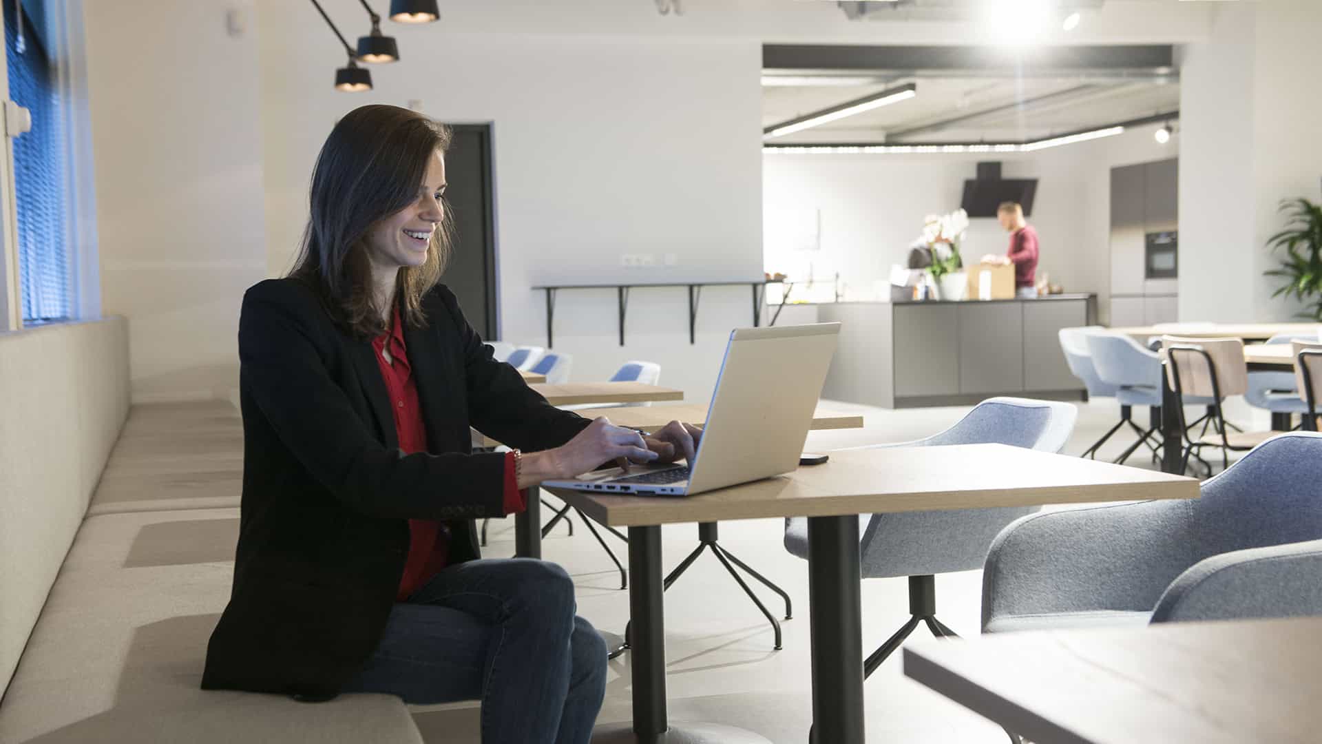 Een collega werkt aan een laptop in een overlegruimte