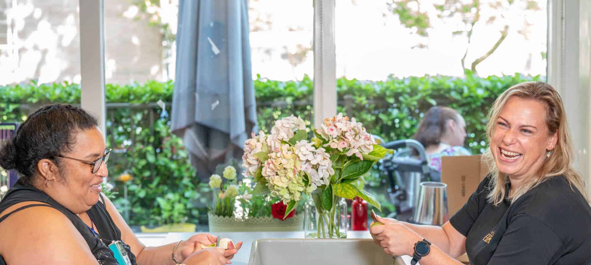 Twee bewoners van Zorggroep Crabbehoff in gesprek bij het raam
