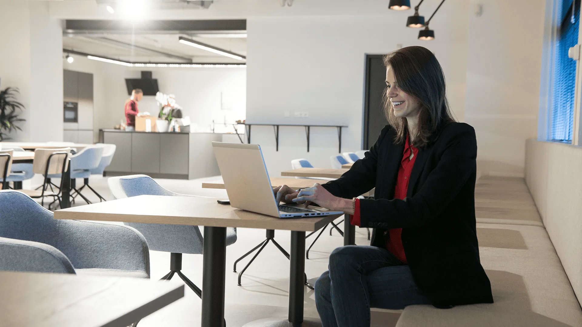 Een collega werkt aan een laptop in een overlegruimte