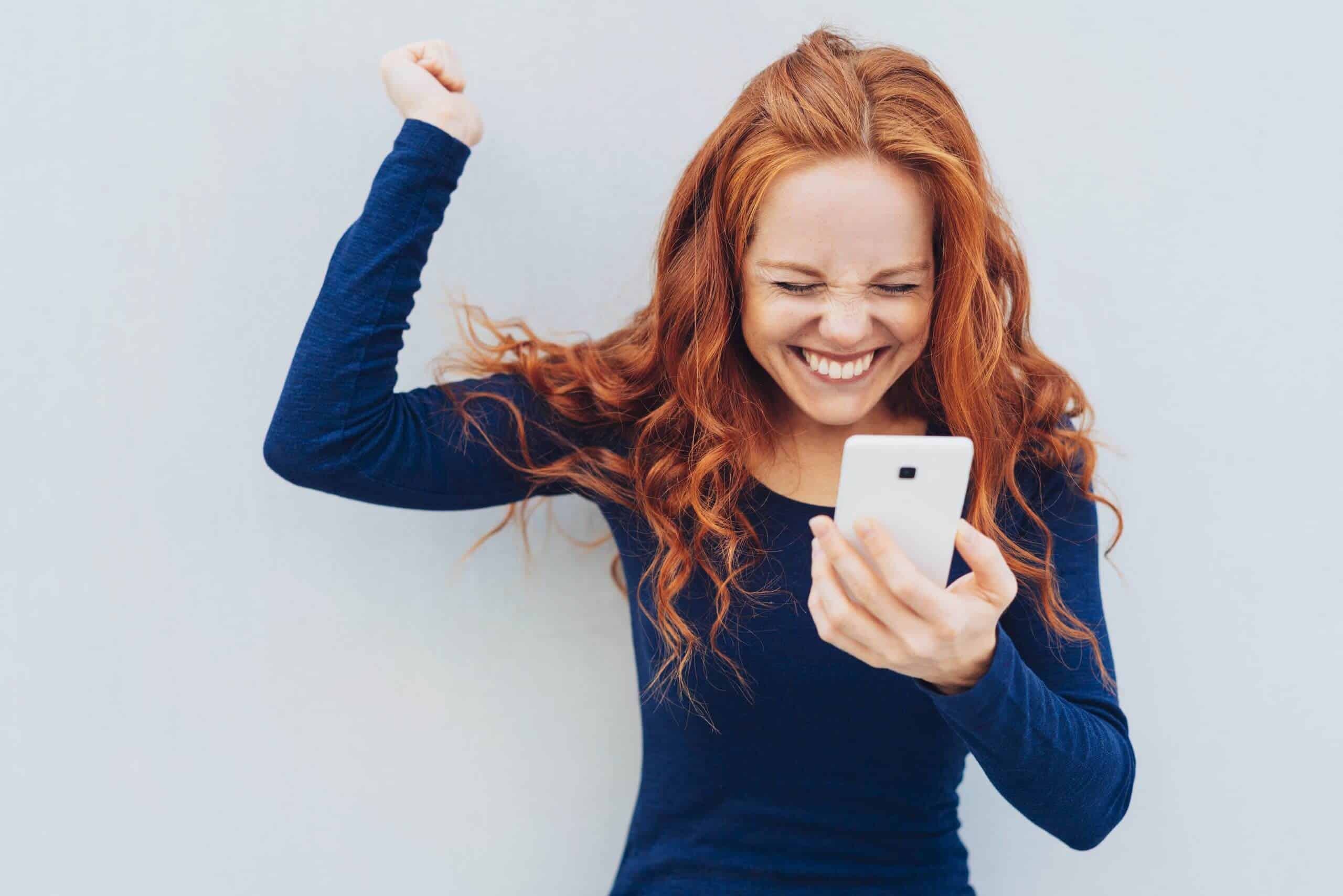 Een lachende vrouw met een telefoon in haar hand