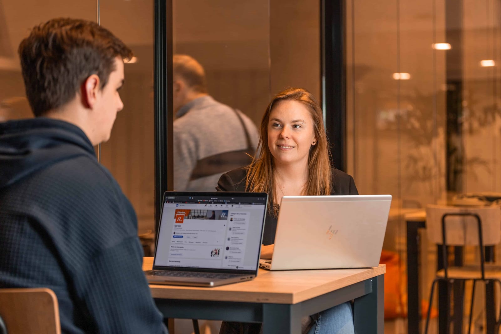 Twee collega's werken samen aan een laptop bij het raam