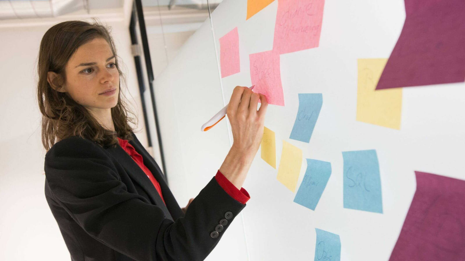 Een collega plakt post-its op een planbord