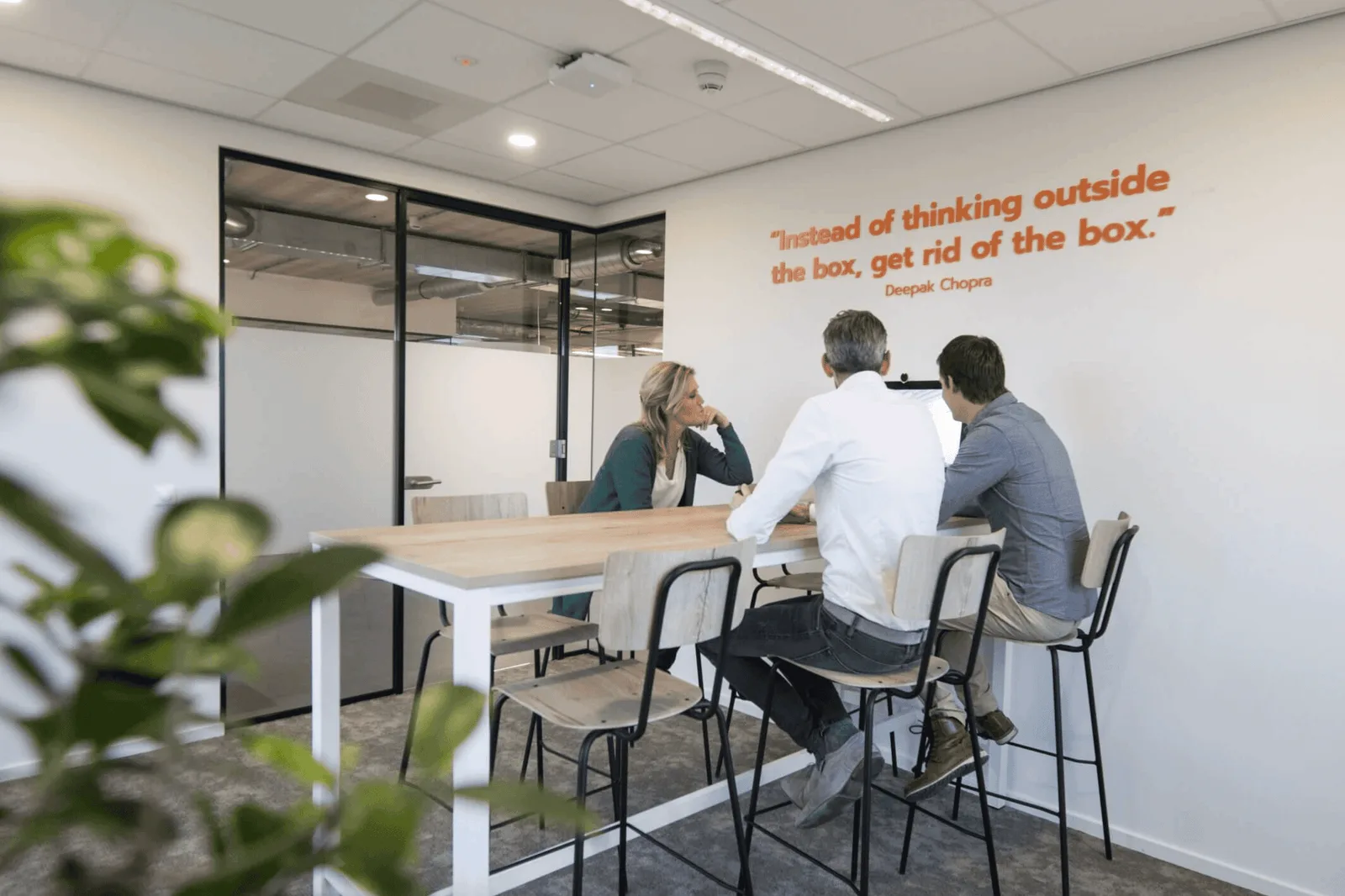 Werkplekken met de tekst Instead of thinking outside the box aan de wand