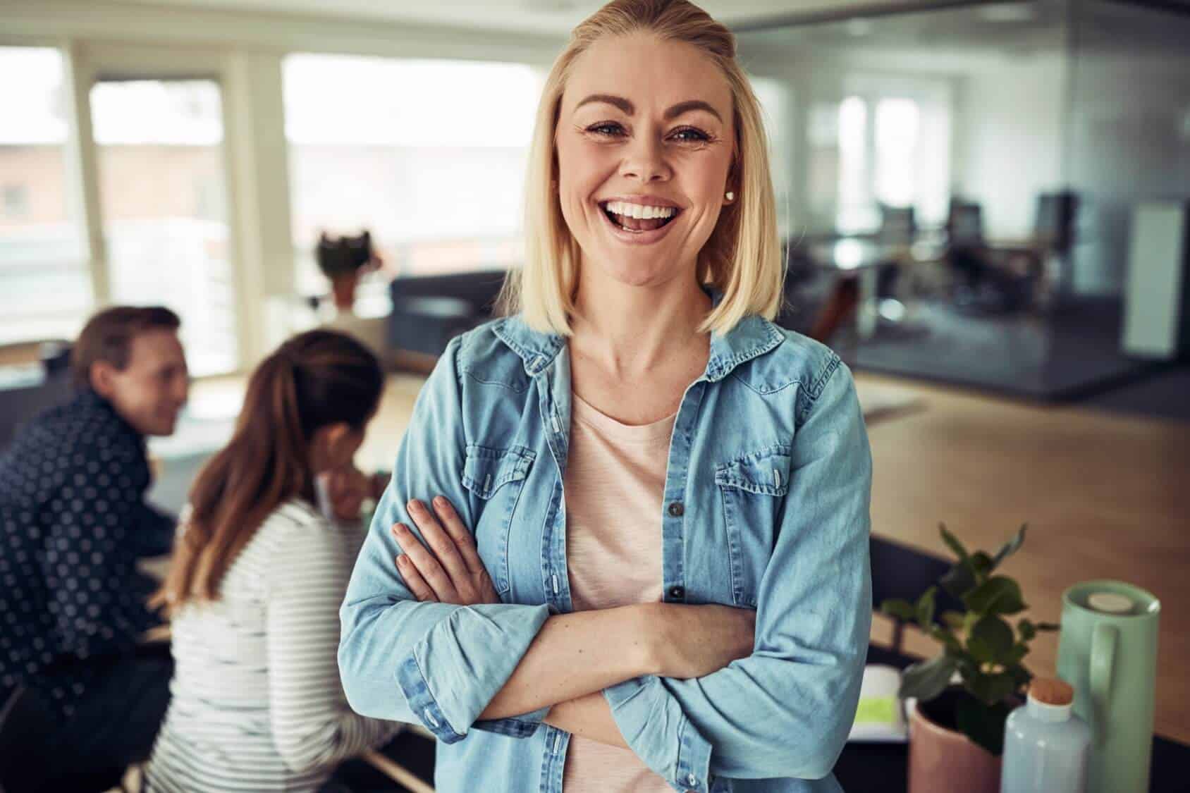 Een lachende collega met de armen over elkaar in het kantoor