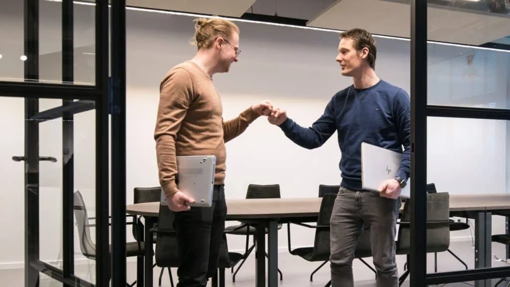 Twee collega's geven elkaar een hand